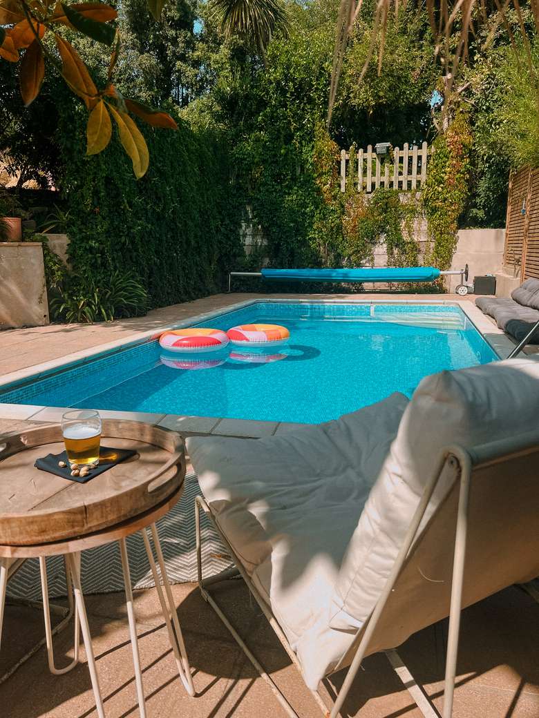 Rings floating in the pool, with a cold drink and pistachios beside the loungers
